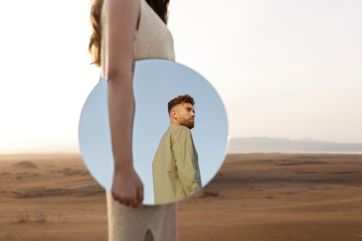 Person lächelt sich selbst im Spiegel an – Symbol für Selbstliebe und ein Leben für sich selbst.