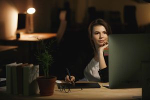 Nachdenkliche Frau arbeitet spät am Laptop und wirkt emotional distanziert.