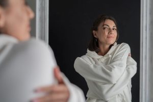 Person schaut selbstbewusst in den Spiegel und erkennt den eigenen Wert.