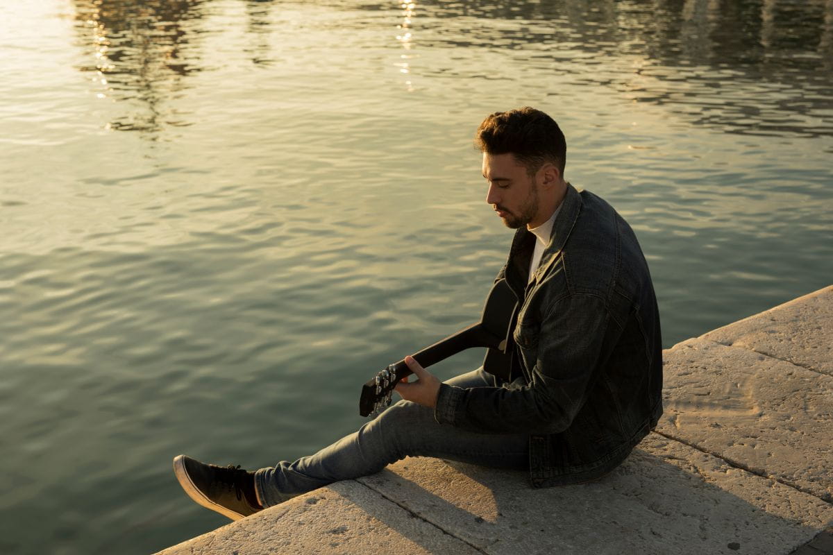 Person sitzt ruhig auf einer Bank am See bei Sonnenuntergang und genießt innere Ruhe