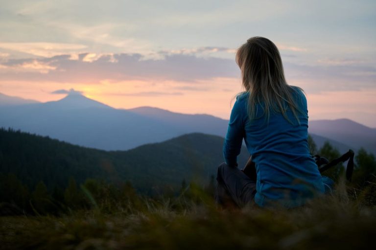 Person blickt hoffnungsvoll in den Sonnenaufgang