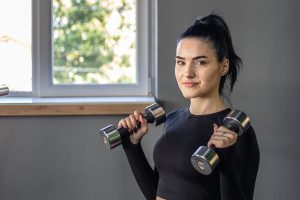 Frau trainiert mit Hanteln im Fitnessstudio zur Stärkung von Körper und mentaler Gesundheit
