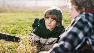 Kind mit Übergewicht sitzt isoliert auf einem Schulhof