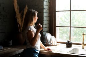 Person blickt nachdenklich aus dem Fenster bei Autoimmunerkrankung und Depression