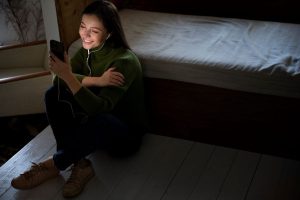Teenager nutzt nachts Smartphone und wirkt müde und gestresst