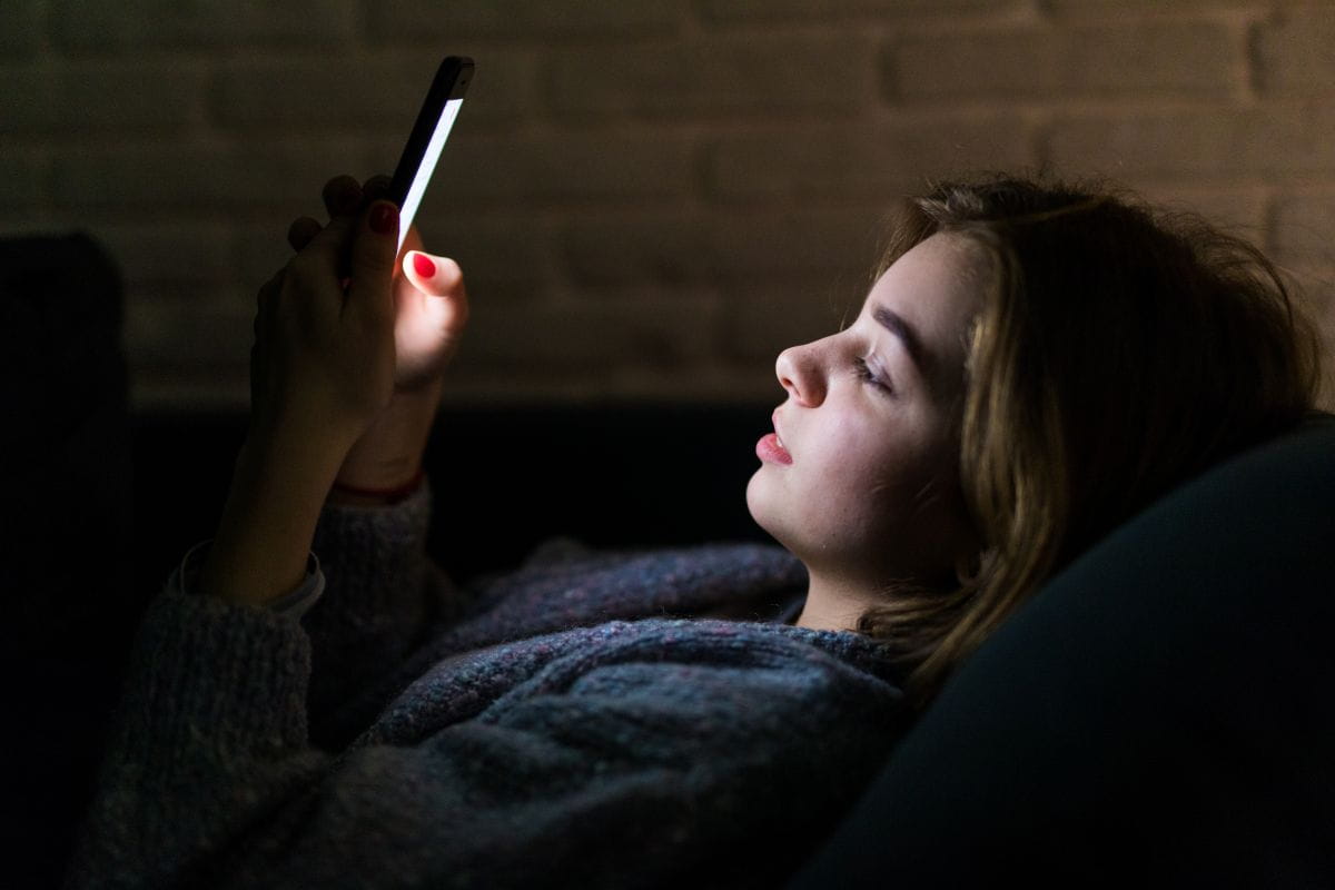 Person schaut nachts auf Smartphone mit Prominenten und fühlt emotionale Verbindung