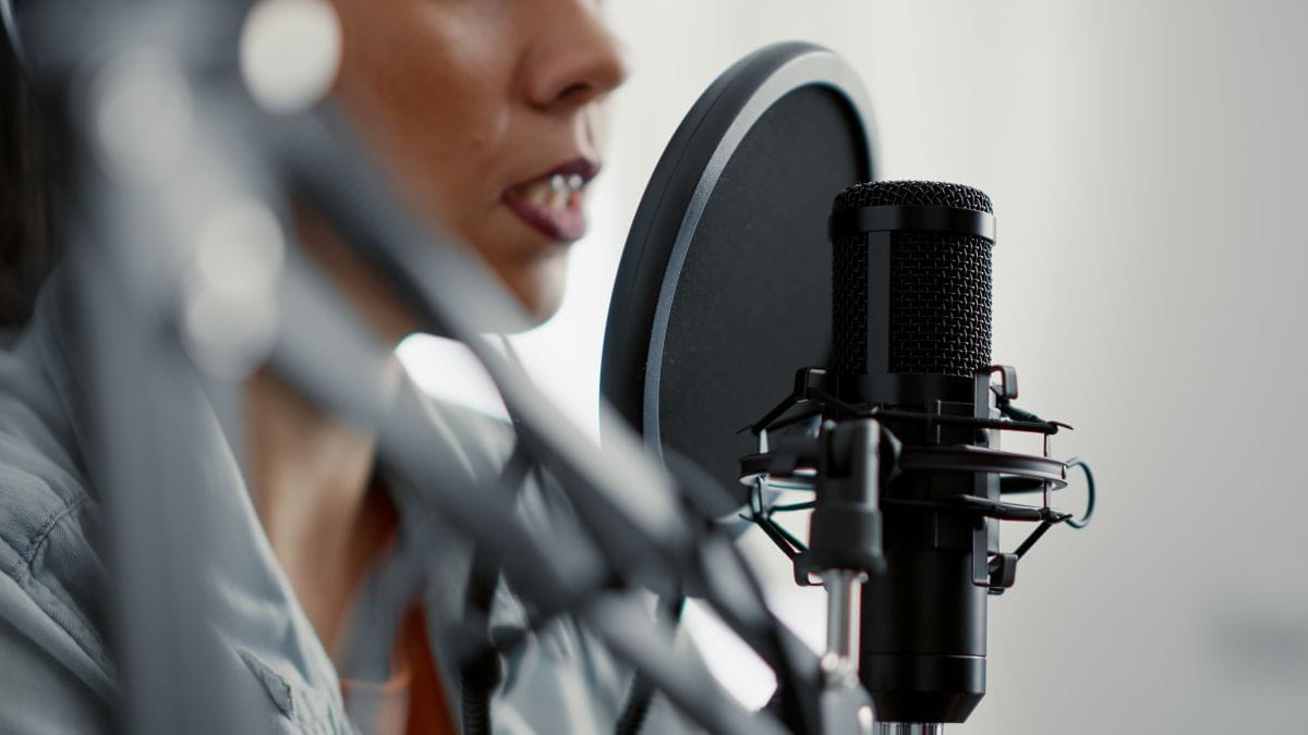 Nahaufnahme eines schwarzen Mikrofons mit daran hängenden Kopfhörern (Symbolfoto für Podcasts).